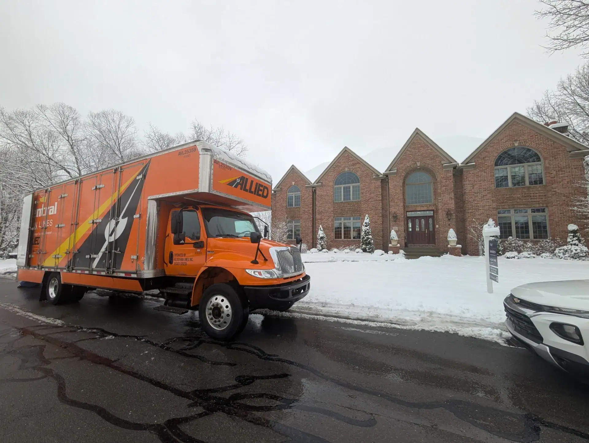 Allied Van Lines truck parked outside a brick home in winter